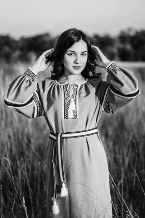 Pretty brunette girl in long embroidery dress outdoorの写真素材