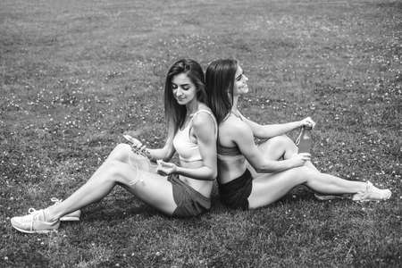 Two pretty sporty girls relaxing after workout outdoor, black and whiteの写真素材