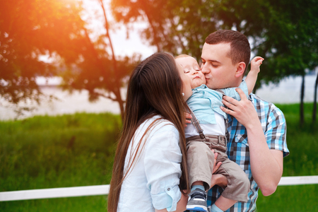Young happy parents playing with little son outdoor in the parkの写真素材