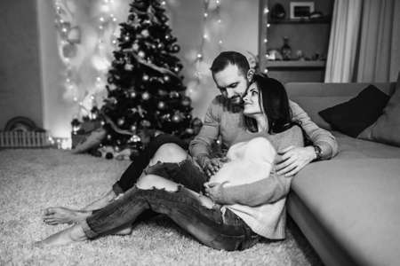 Happy pregnant woman with husband at home with christmas decorationsの写真素材