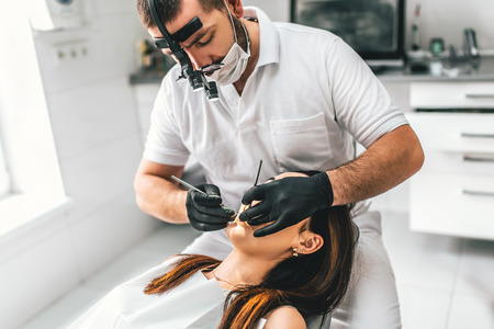 Dentist working in dental clinic with patient in the chairの写真素材