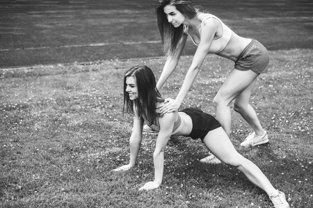 Two pretty sporty girls workout together outdoor, black and whiteの写真素材