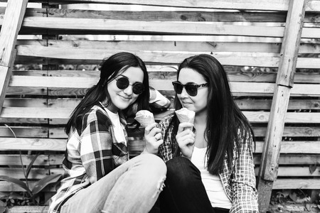Two pretty girls talking and eating ice cream outdoor, black and whiteの写真素材