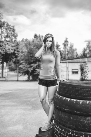Sporty girl near huge old tires outdoor, black and whiteの写真素材
