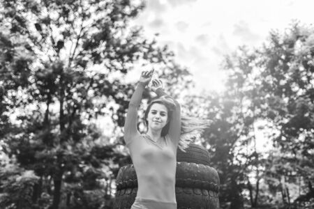 Sporty girl near huge old tires outdoor, black and whiteの写真素材