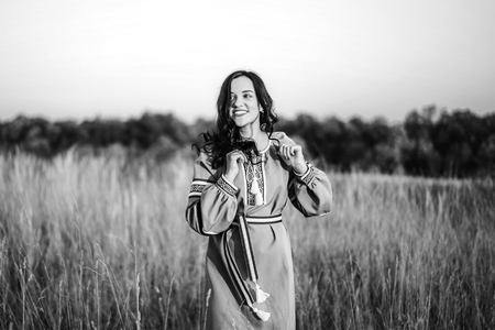 Pretty brunette girl in long embroidery dress outdoorの写真素材