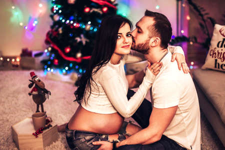 Pregnant mother and her husband at home with christmas decorationsの写真素材