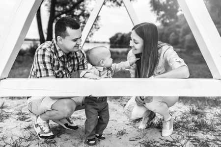 Young happy parents playing with little son outdoor in the park, black and whiteの写真素材