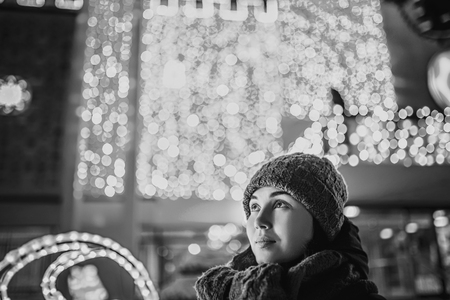 Girl outdoor in cold weather with christmas lights behindの写真素材