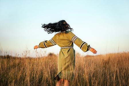 Pretty brunette girl in long embroidery dress outdoorの写真素材