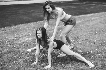 Two pretty sporty girls workout together outdoor, black and whiteの写真素材