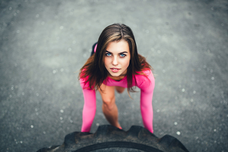 Young sporty girl workout outdoor with big tireの写真素材