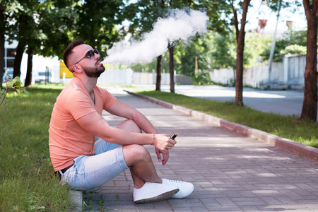 Vaper with beard with electronic cigarette outdoorの写真素材