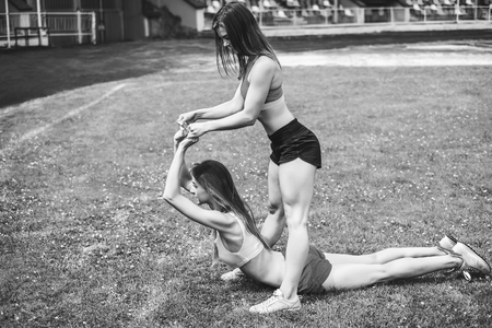 Two pretty sporty girls workout together outdoor, black and whiteの写真素材