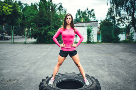 Young sporty girl workout outdoor with big tireの写真素材