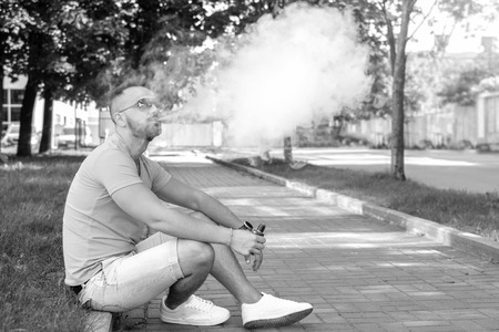 Vaper with beard with electronic cigarette outdoorの写真素材