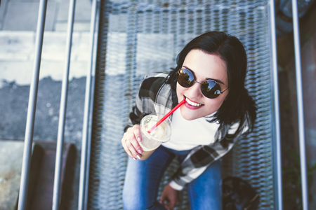 Pretty brunette girl drinking cold coffee outdoorの写真素材