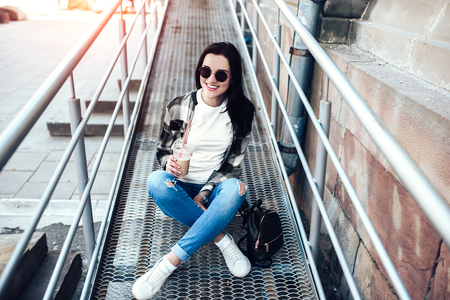 Pretty brunette girl drinking cold coffee outdoorの写真素材