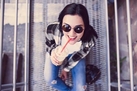 Pretty brunette girl drinking cold coffee outdoorの写真素材