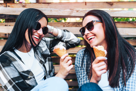 Two pretty brunette women eating ice creamの写真素材