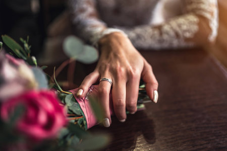 Brideâs hand with wedding ring and flower bouquetの写真素材