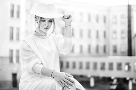 Pretty woman in white vintage dress sitting outdoorの写真素材