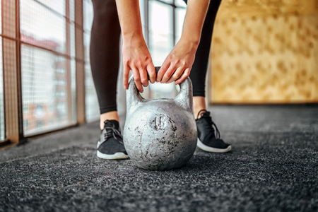 Sporty girl lifting kettlebell from the floor in the gymの写真素材