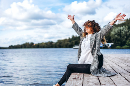Pretty girl with curly hair relaxing near lakeの写真素材