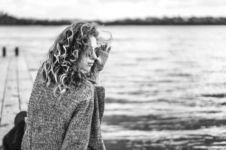 Pretty girl with curly hair relaxing near lakeの写真素材