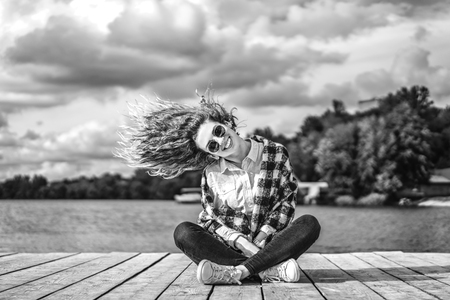 Pretty girl with curly hair relaxing near lakeの写真素材