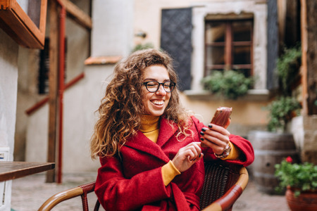 Pretty girl with curly hair using phone outdoorの写真素材