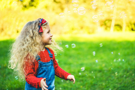 Pretty little girl blowing bubbles in the parkの写真素材