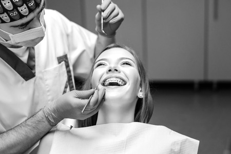 Dentist examine female patient with braces in denal officeの写真素材