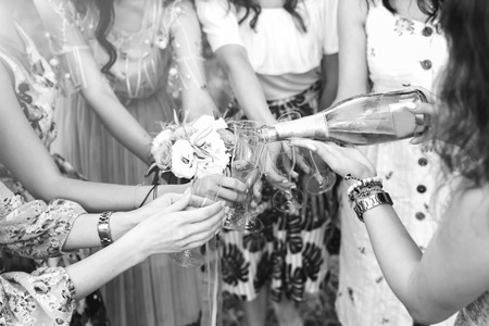 Champagne with glasses in girls hands at hen party outdoorの写真素材