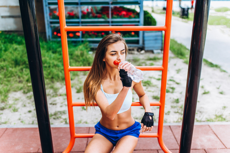 Cute sporty girl relaxing after outdoor training with bottle of water in hands.の写真素材