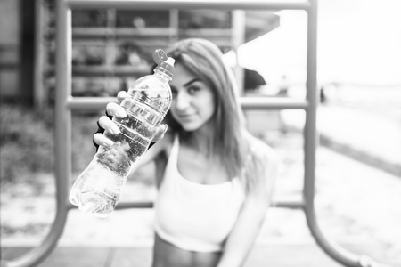 Cute sporty girl relaxing after outdoor training with bottle of water in hands.の写真素材