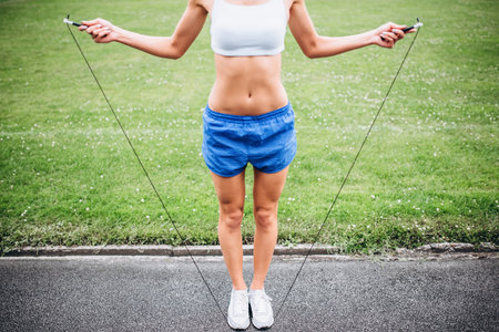 Girl with sporty body jumping rope outdoorの写真素材