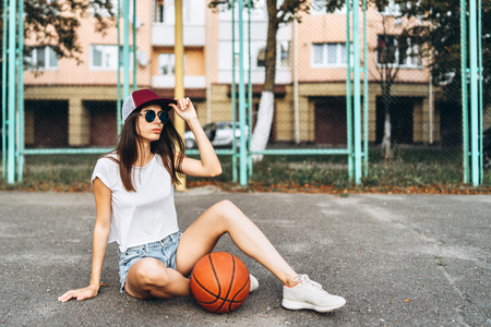 Pretty young sporty girl with basketball ball outdoorの写真素材