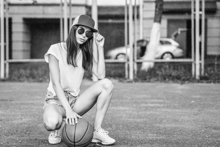 Pretty young sporty girl with basketball ball outdoorの写真素材