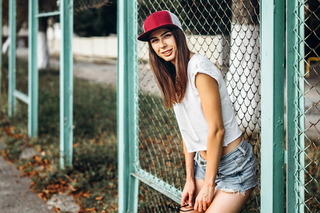 Pretty sporty brunette girl near metal grid on playgroundの写真素材