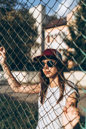 Pretty sporty brunette girl near metal grid on playgroundの写真素材