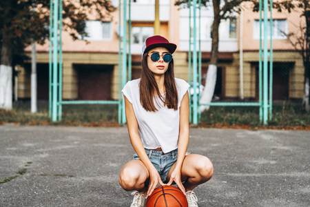 Pretty young sporty girl with basketball ball outdoorの写真素材