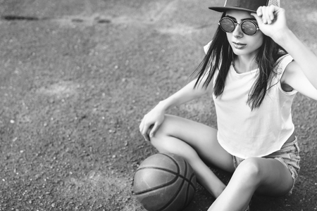 Pretty young sporty girl with basketball ball outdoorの写真素材