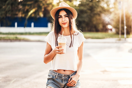 Pretty brunette tourist girl with cup of cold coffee outdoorの写真素材