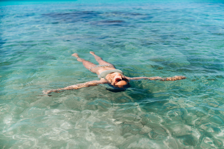 Pretty pan asian girl relaxing and swimming in blue sea waterの写真素材