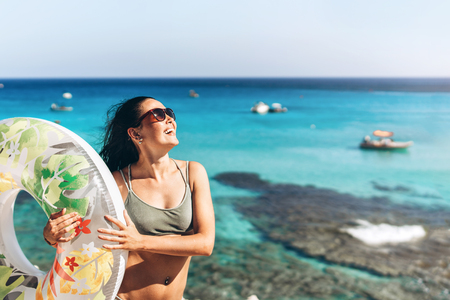 Pretty happy pan asian girl with big float and blue sea behind on backgroundの写真素材