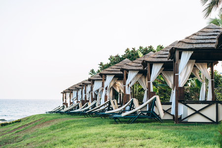 Line of bungalow on the beach with grass and sunbedsの写真素材