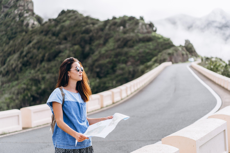 Pretty brunette girl in sunglasses outdoor in the mountains with mapの写真素材