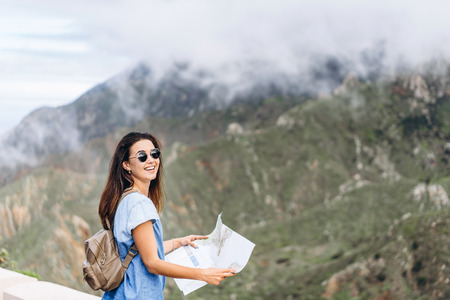 Pretty brunette girl in sunglasses outdoor in the mountains with mapの写真素材