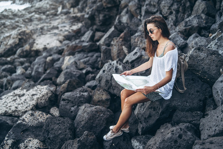 Pretty long hair tourist girl relaxing on the stones near seaの写真素材